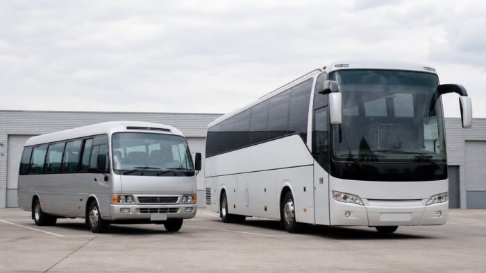 Minibus and full-size charter coach parked side by side for a size comparison
